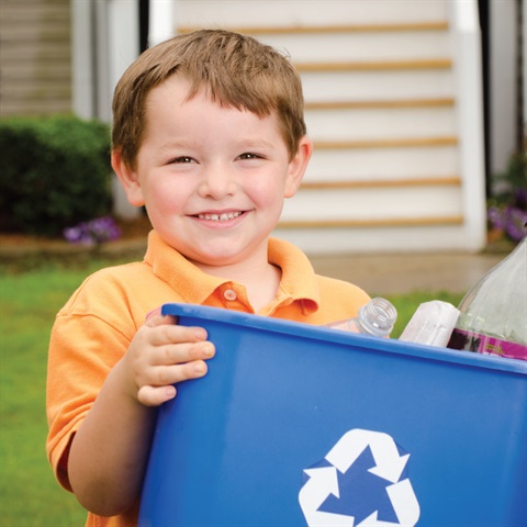 Recycling concept with young child carrying recycling bin to the curb at his house